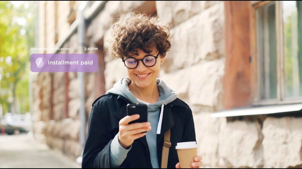 A girl with a mobile phone and a cup of coffee in her hands